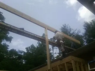 Carpenter setting a ridge beam over a new addition frame — Ice Dam Removal by Roofing Brothers in Marshall